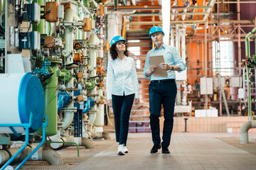 Inspectors team checking machine while walking in workshop