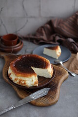 Basque burnt cheesecake in a plate on a wooden board. Cheesecake San Sebastian on a beige table.