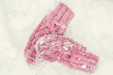 Pink wool mittens on white snow