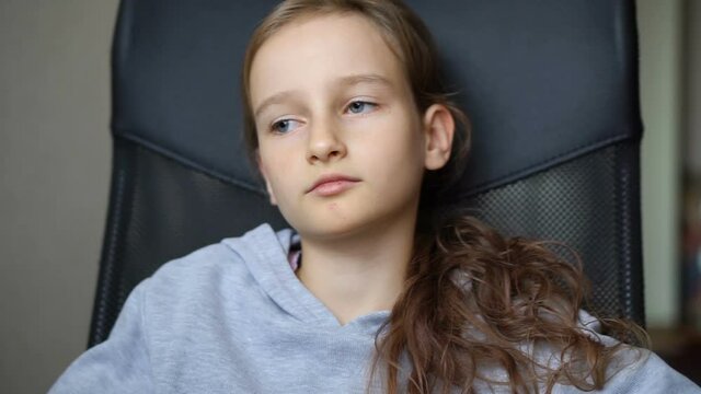 Little sad girl is sitting on black office chair, punishment, serious face