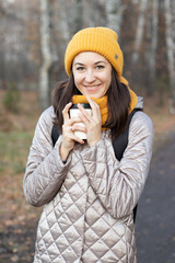 girl walks in the autumn park with a cup of coffee