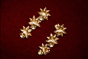 Gold holographic gift bows in diagonal rows on red velvet background. Classic holiday colors, luxury festive atmosphere