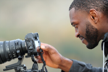 Man with black skin checking photos on mirrorless camera - Powered by Adobe