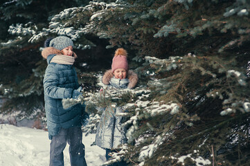 Two happy girls play and rejoice in the winter snowy forest
