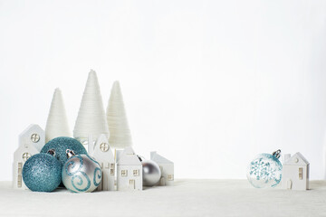 New Year's composition of white wooden houses and blue Christmas balls on a white background. Happy...