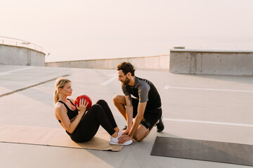 Young man and woman working out with medicine ball together on parking