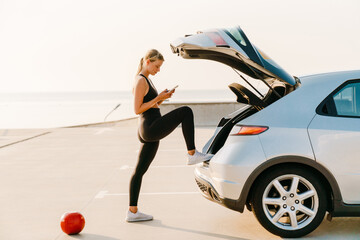 Young woman using mobile phone during workout on parking