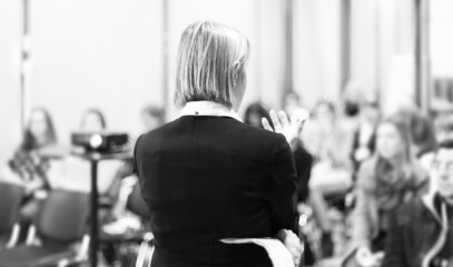 Female public speaker giving talk at Business Event.