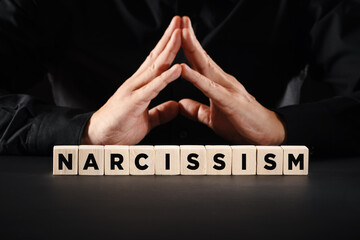 Man with clasped hands with the word narcissism. Personal ego or selfishness concept.