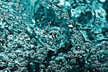 Boiling water bubbles. Air bubble background. Fizzy water texture. Black water pattern. Dark wet background. Turqoise color water closeup.