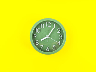 Green alarm clock on bold yellow background. Time concept