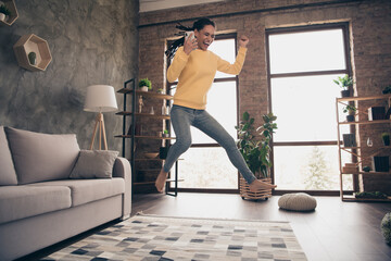 Photo of funny sweet young lady wear yellow pullover rising fist holding modern gadget jumping...