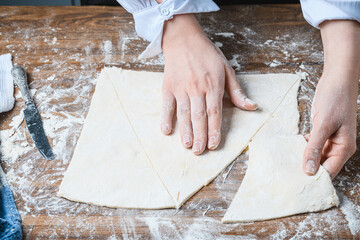 The chef manually makes croissants on the table with ingredients.