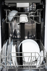 Clean plates after washing in dishwasher at home.  Modern kitchen with dishwashing machine....