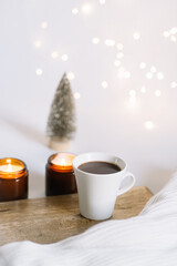 new year christmas card. Christmas tree, lights of garlands, two lighted candles and a cup of coffee. comfort and hygge