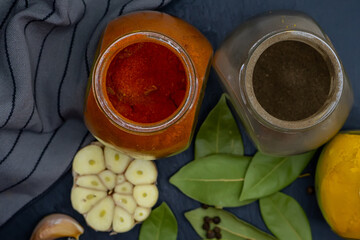 Top view. Jars of spices, bay leaf, garlic and a kitchen towel on a dark background.