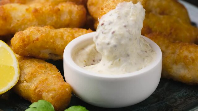 Dipping Crispy Fish strips in tartar sauce.