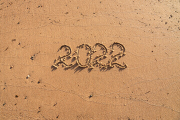 2022 written on a sandy beach. Summer holidays in 2022