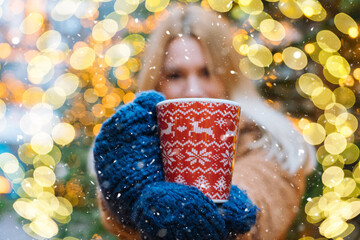 Girl walking in Christmas traditional market decorated with holiday lights in the evening. Winter portrait beautiful young woman outdoors in front of Xmas holidays decorations