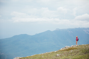 female traveler standing on top of a mountain looking at the view