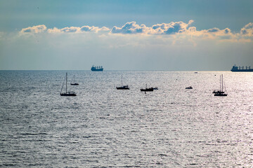 Yachts at sea and ships in the background.