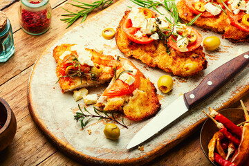 Fried schnitzel with olives and tomato