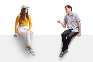 Casual young people sitting on a blank panel and having a conversation