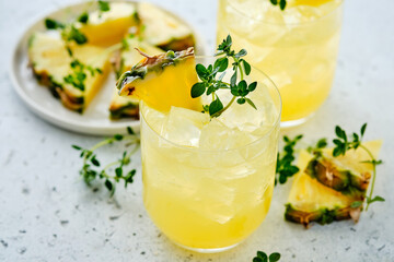 Pineapple cocktail with pulp in a glass and thyme.