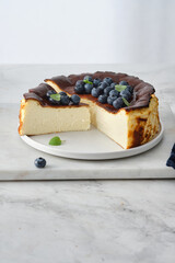 Basque cheesecake on a marble background with berries.