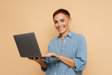 Senior ginger woman smiling while posing with laptop