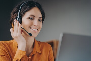 Pleasant woman Spanish speaking call center employee in wireless headset talking with client