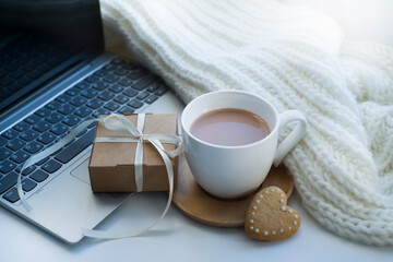 laptop, coffee cup, white knitted scarf, heart-shaped cookies, gift. romantic background, valentine's day card. with love.