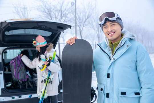 a happy Ski young man holding snowboard equipment

