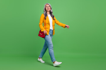 Full body profile side photo of lovely retired woman walk vacation casual clothes isolated over green color background