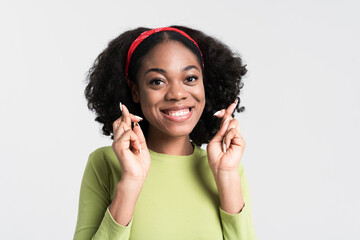 Young black woman smiling and holding fingers crossed for good luck