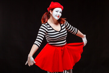 Portrait of female mime artist performing, isolated on black background. Woman in striped clothes...