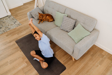 Young hispanic woman smiling and doing exercise during yoga practice