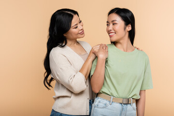 happy asian woman hugging adult daughter isolated on beige