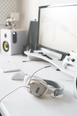White large gaming headphones are on the table. Close-up in a bright interior