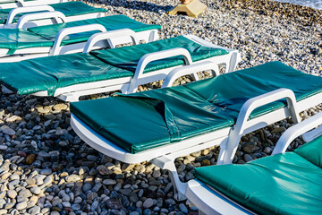 Empty chaise lounges on pebble at the beach