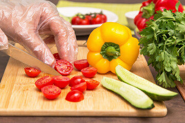 Different vegetables for cooking healthy vegetarian vegan diet food. Chef hands in cellophane gloves cutting tomato close up