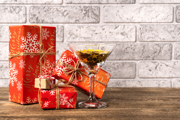 Christmas gifts in a red wrapper in different sizes with a martini glass with glitter on a brick...
