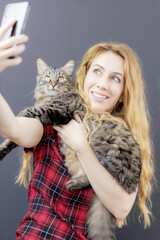 Smiling girl takes a selfie with a beautiful tabby cat. Photo with your favorite pet