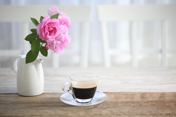 Fototapeta na wymiar Coffee in glass cup and pink rose on wooden table indoor