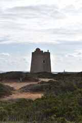 Fototapeta na wymiar An old tower and a lighthouse in Las Salinas Natural Park, Ibiza