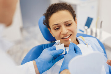 Dentist holding teeth color palette with patient