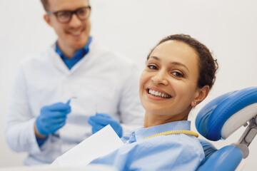 Woman posing at camera in dental chair with dentist