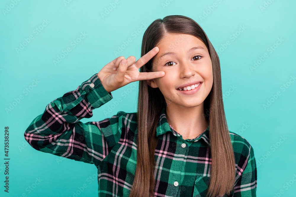 Poster photo of cute sweet school girl dressed checkered clothes smiling showing v-sign cover eye isolated 