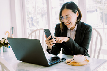 Woman working online through mobile phone and notebook computer.