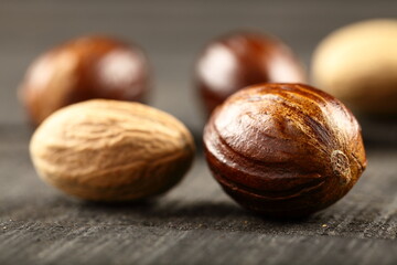 Organic wild nutmeg sees, on a rustic kitchen table background.